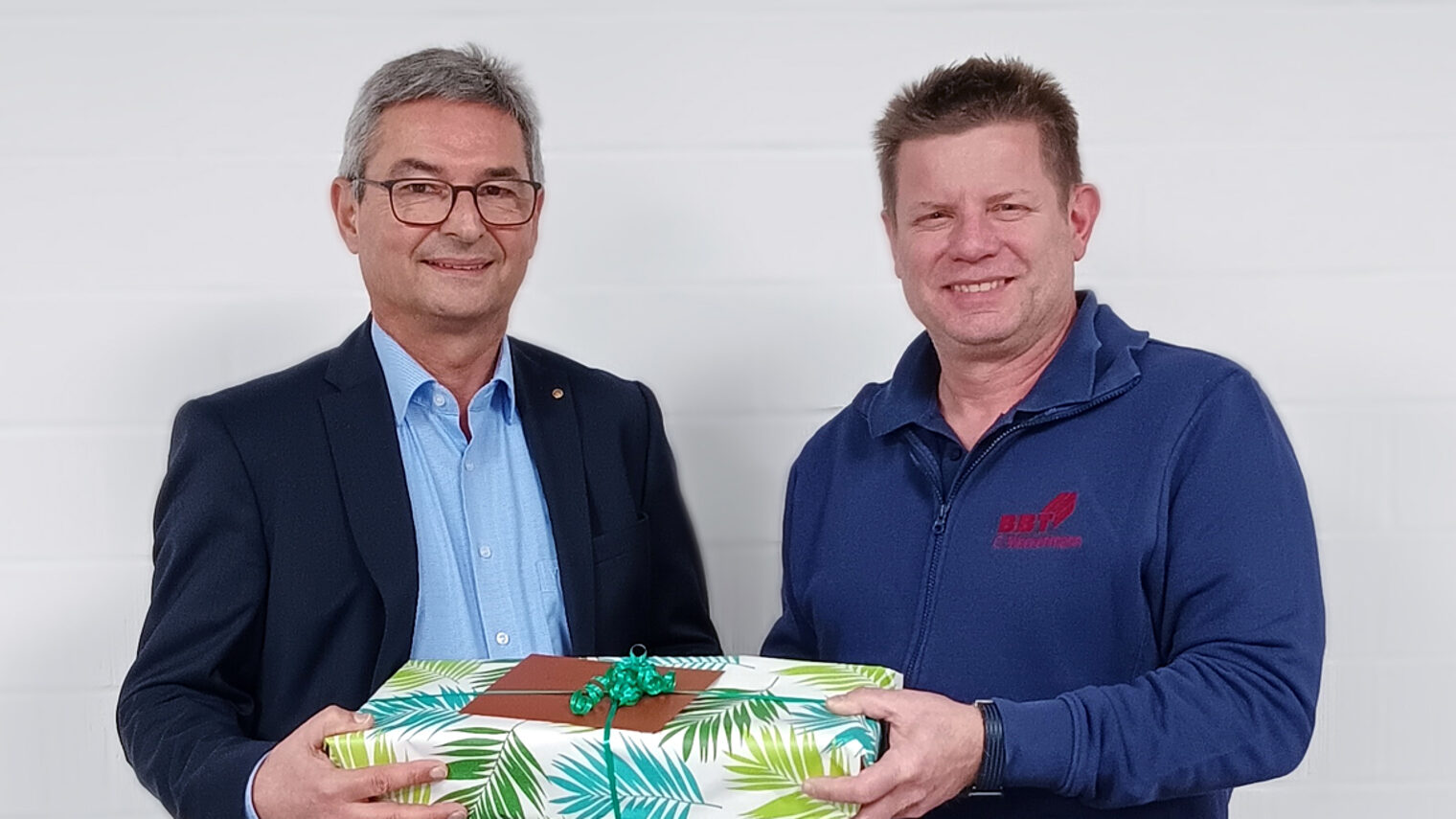 Chef ueberreicht Mitarbeiter Geschenk zum 15 jaehrigen Jubilaeum