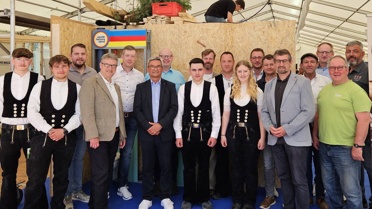 Funktionsträger aus Handwerk, Bildung und Innungen sowie Zimmerer in Kluft vor dem live gebauten Messehaus im Handwerkerzelt der Ausbildungsbörse PROTUT in Tuttlingen.