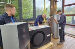 Drei Personen arbeiten in einer Ausbildungswerkstatt an Heizungs- und Anlagentechnik