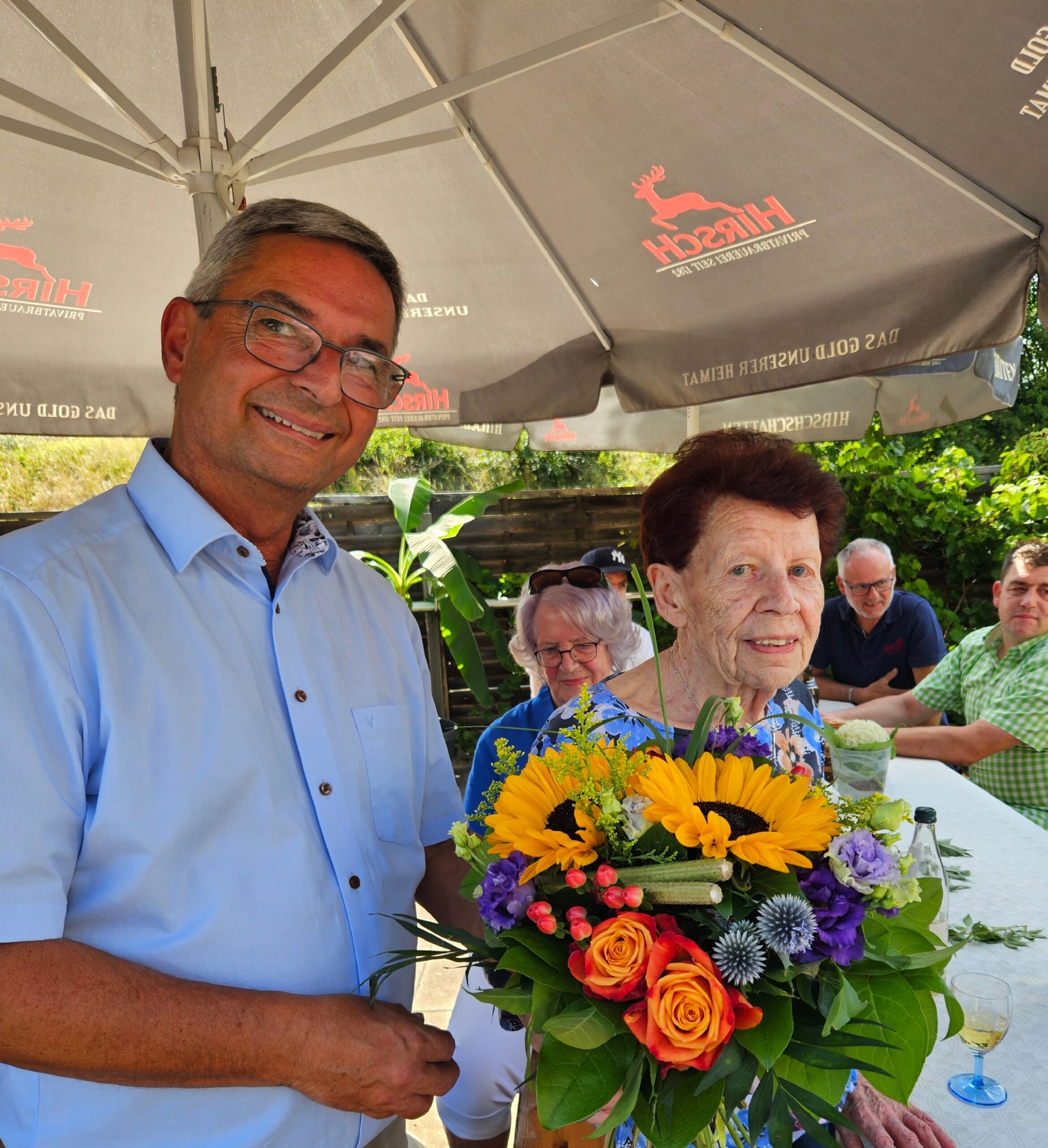 Geschäftsführer Roland Aicheler überreicht Frau Haustein einen Blumenstrauß zum 90. Geburtstag beim BBT-Ehemaligentreffen