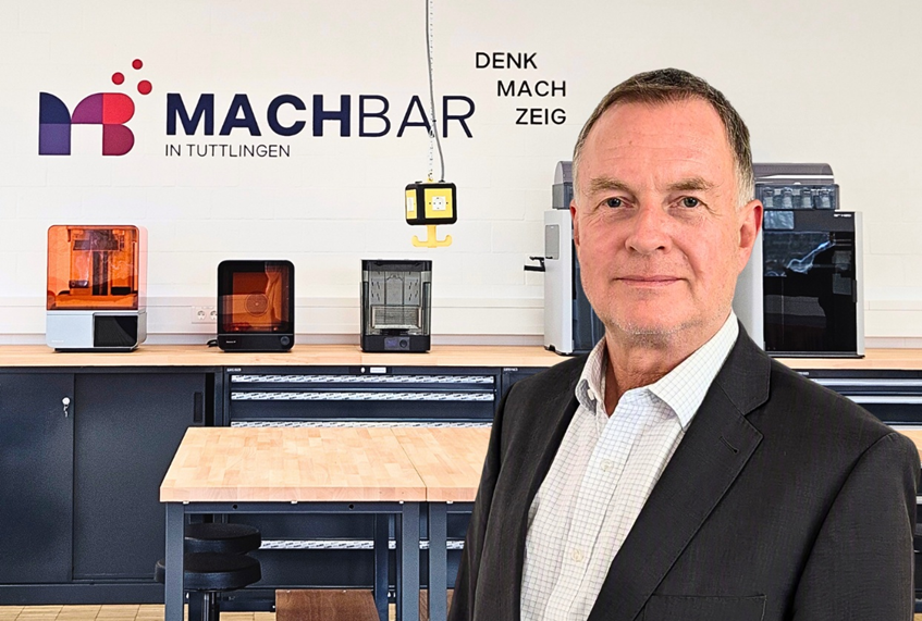 Prof. Dr. Jürgen Wagenmann im Kreativraum MACHBAR in Tuttlingen vor Logo und den Bereichen Denk, Mach, Zeig