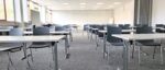 Moderner Schulungsraum mit Tischen, Stühlen und Präsentationstechnik für Seminare und Konferenzen