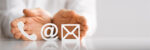 Telefonhörer-, E-Mail- und At-Symbol vor schützend gehaltenen Händen.