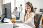Mitarbeitende mit Headsets arbeiten in einem Beratungsbüro an Computerarbeitsplätzen.
